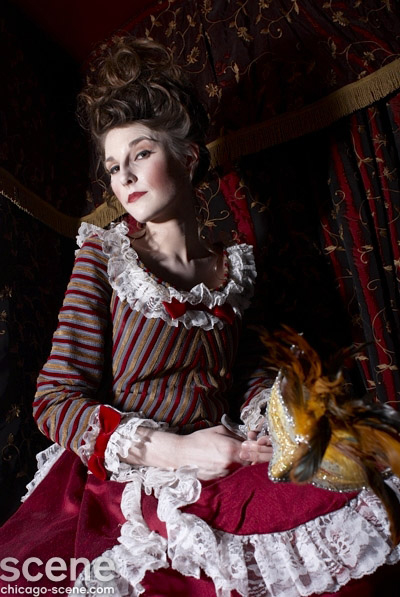 Marie Antoinette-inspired editorial for Chicago Scene Magazine — model with a tall powdered updo, wearing a striped 18th-century jacket with white ruffled lace cuffs, holding an ornate feathered masquerade mask. Hair by Angeleah Daidone.