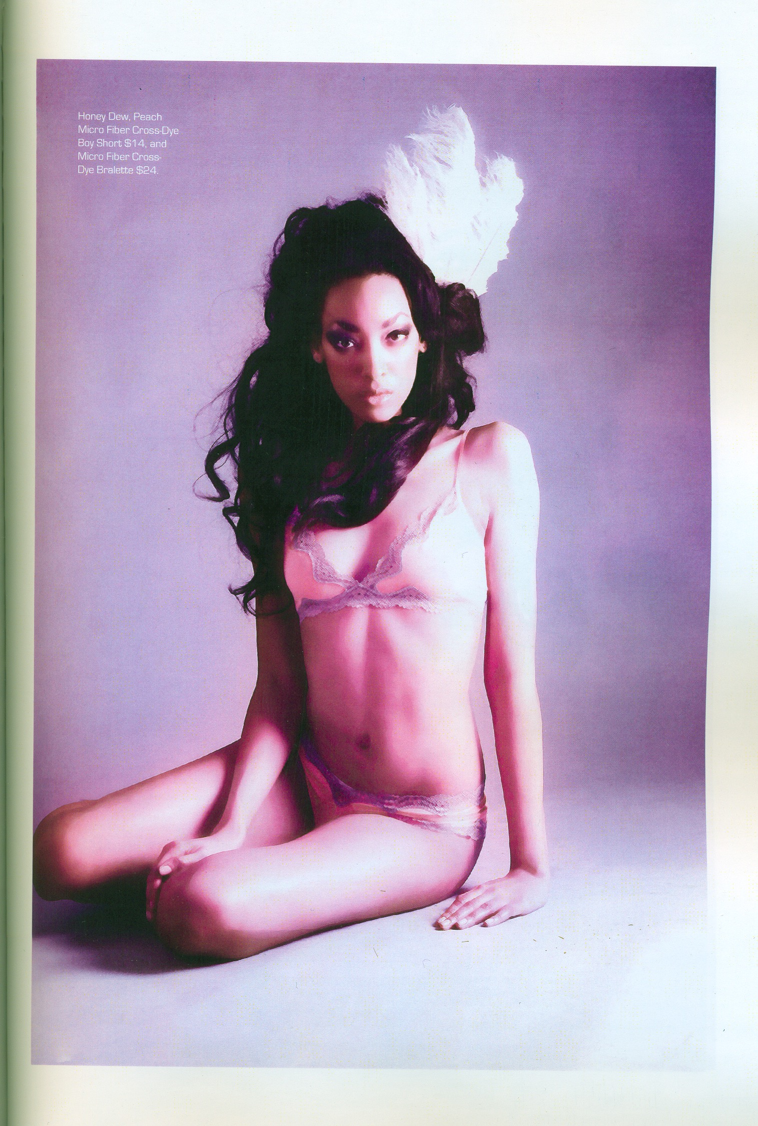 Moda Fashion Gazette tear sheet — model with long teased dark hair and a tall white feathered headpiece, seated in pale pink lingerie against a lavender backdrop. Hair by Angeleah Daidone.