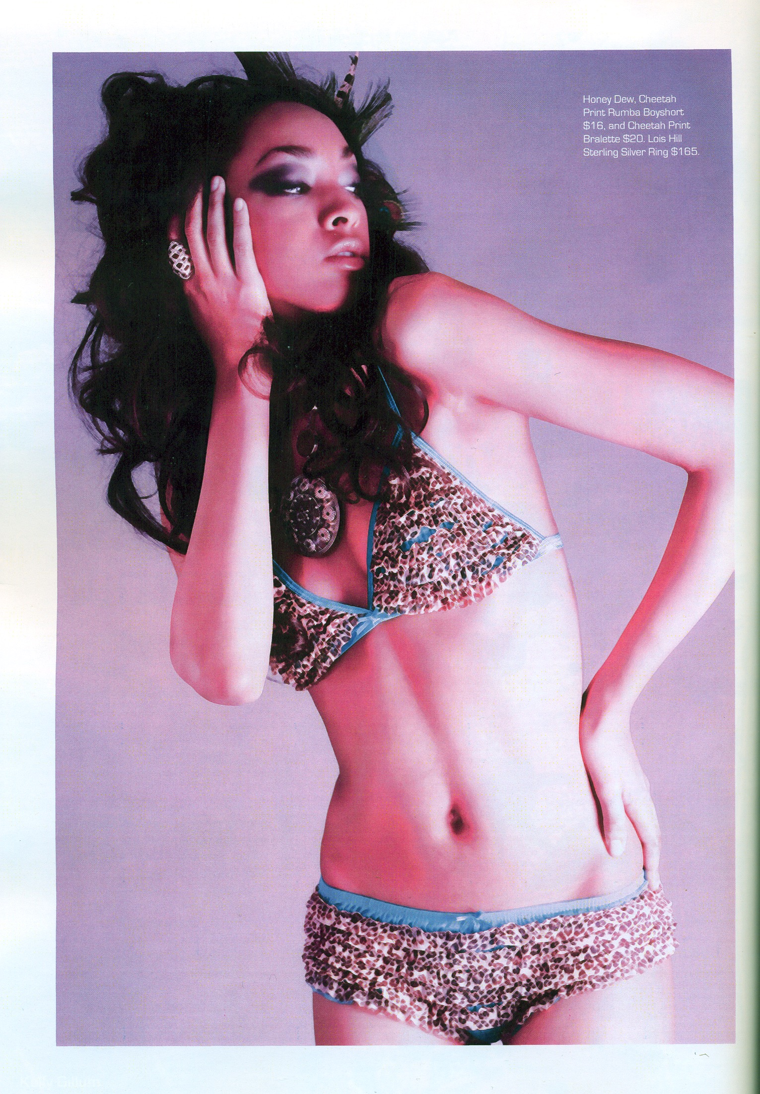 Moda Fashion Gazette tear sheet — model with voluminous teased dark hair and bold eye makeup, wearing a beaded animal-print bra and shorts set against a lavender backdrop. Hair by Angeleah Daidone.