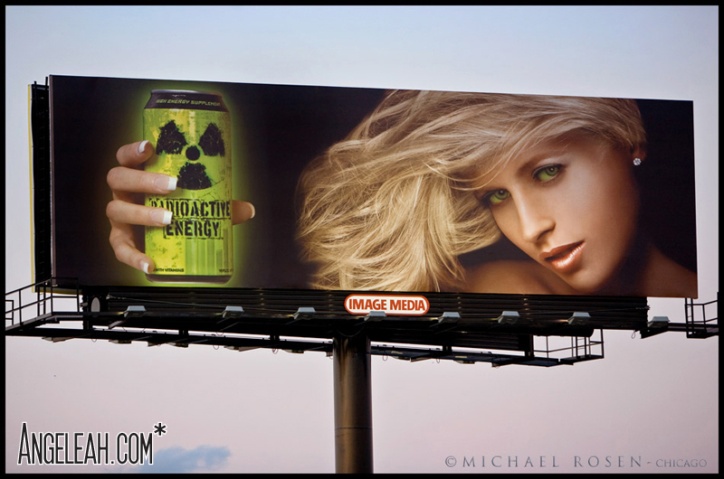 Outdoor billboard for Radioactive Energy Drink showing a blonde model with windswept hair holding the green can next to her face. Image Media branding visible; photographed by Michael Rosen. Hair by Angeleah Daidone.